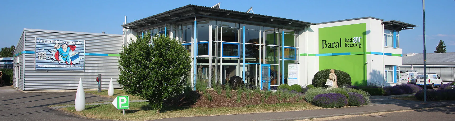 Das Firmengebäude von Baral bad & heizung zeigt eine Kombination aus Glas- und Metallfassade, umgeben von gepflegten Grünanlagen.