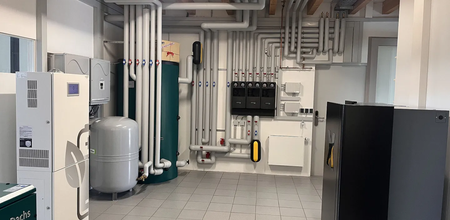 In einem Ausstellungsraum sind mehrere große Tanks, Wärmespeicher, ein Blockheizkraftwerk sowie ein Batteriespeicher über ein komplexes Rohrleitungssystem miteinander verbunden.