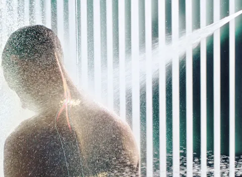 Mann genießt Aquapressur mit Regendusche von Dornbracht.