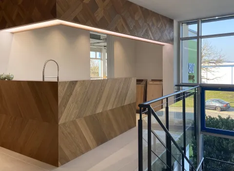 Eine moderne Küche von Trapa mit einer Arbeitsinsel aus diagonal verlegtem Holz in warmen Brauntönen und einer eleganten, freistehenden Armatur. 