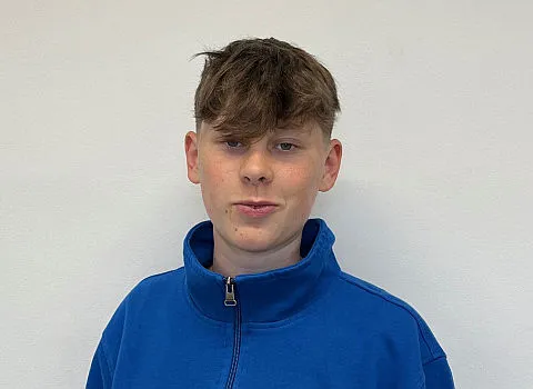 Azubi Arno Neumark in blauer Jacke vor neutralem Hintergrund.