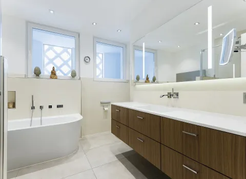 Ein helles Komfortbad mit hellen Fliesen, einer freistehenden Badewanne und einem großzügigen Waschtisch mit dunklem Holzdekor. 