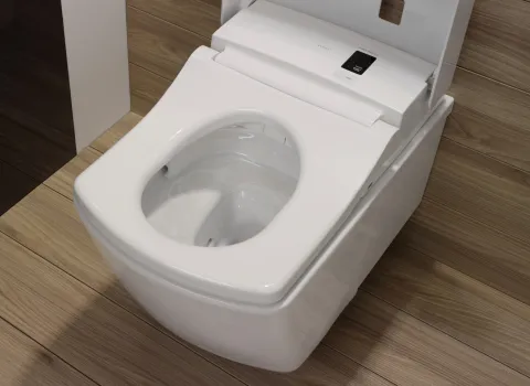 Ein weißes Toto Neorest AC WC mit modernem Design, integriertem Bedienfeld und offenem Deckel, platziert auf hellem Holzfußboden.