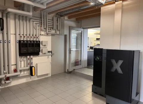 Ein Ausstellungsraum für Energiesysteme zeigt ein modernes E3/DC PRO Speichersystem mit großem X-Symbol im Vordergrund.
