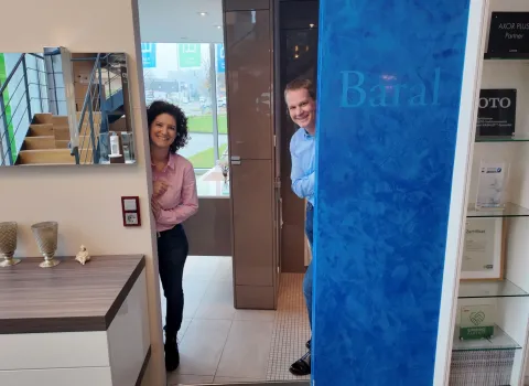Carina Baral und Tim Baral stehen lächelnd im Eingangsbereich des Firmengebäudes der Baral GmbH.