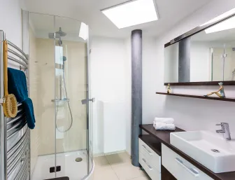 Ein modernes Badezimmer mit einer Eckdusche, die eine Glasabtrennung und eine Regenbrause besitzt.