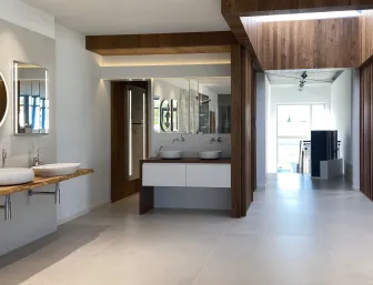 Ein großzügiger Badezimmer-Showroom mit modernen Waschbecken, die auf schwebenden Holzplatten montiert sind und von runden sowie rechteckigen Spiegeln begleitet werden. 