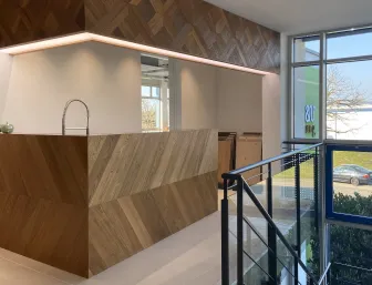 Eine moderne Küche von Trapa mit einer Arbeitsinsel aus diagonal verlegtem Holz in warmen Brauntönen und einer eleganten, freistehenden Armatur. 