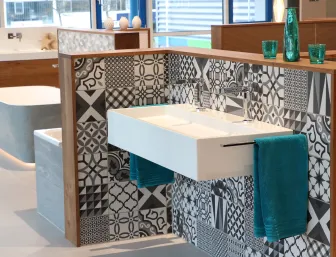 Ein modernes Badezimmer-Design mit einem schwebenden, weißen Waschbecken, das vor einer Wand mit verschiedenen schwarz-weißen Fliesenmustern installiert ist.