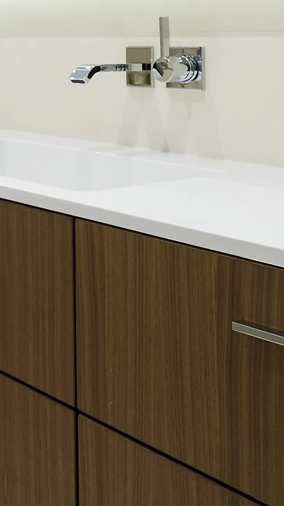 Großer Waschtisch mit Holzfronten und weißer Arbeitsplatte, integriertem Waschbecken und Unterputz-Wandarmatur. 