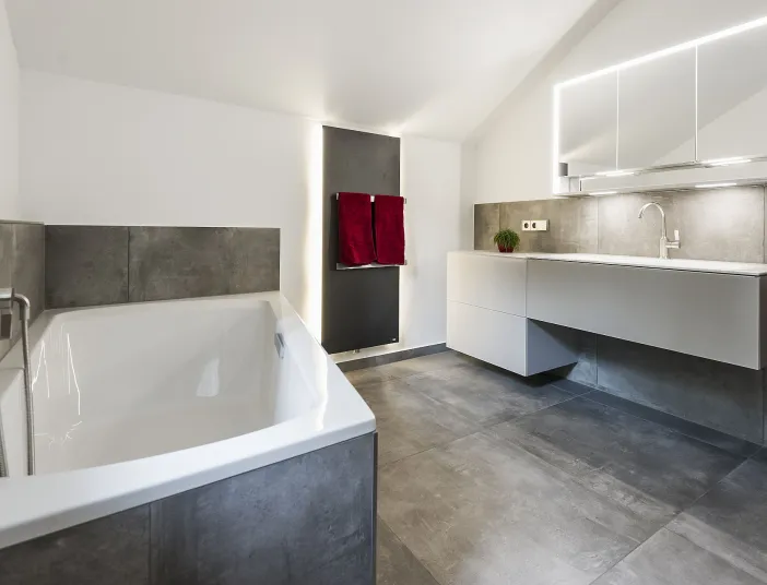 Badezimmer mit dreitürigen Spiegelschrank, Designheizkörper und Einbaubadewanne von Mauersberger.